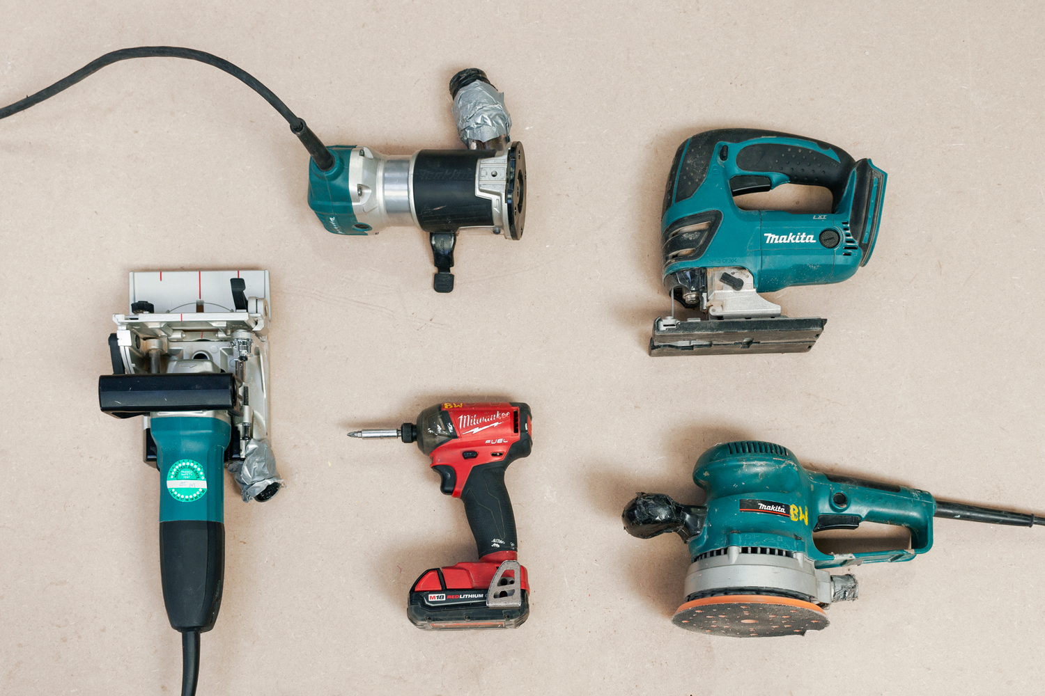 neatly laid out power tools: a drill, router and Makita angle grinder included