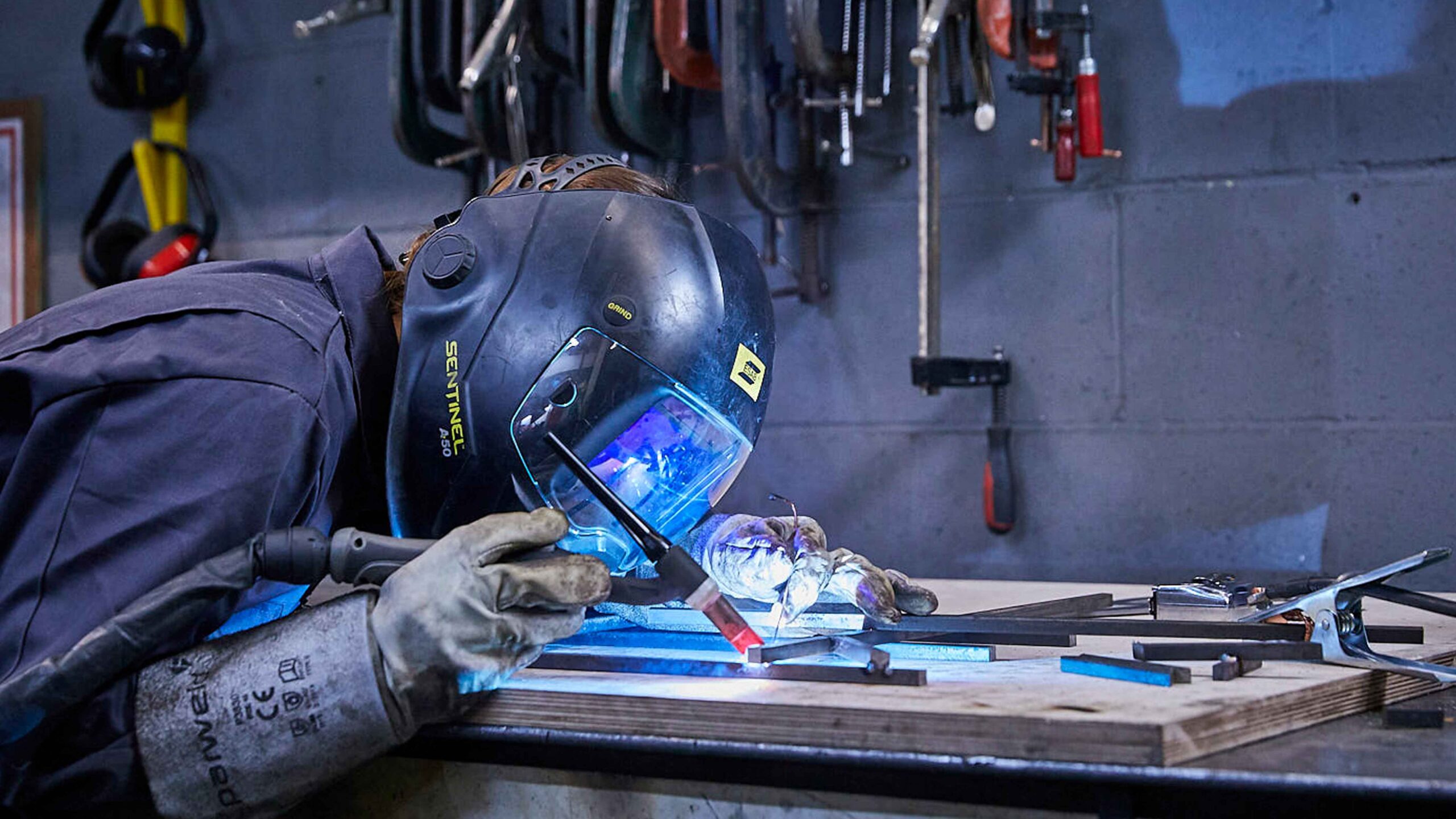 person tig welding at metalwork bench