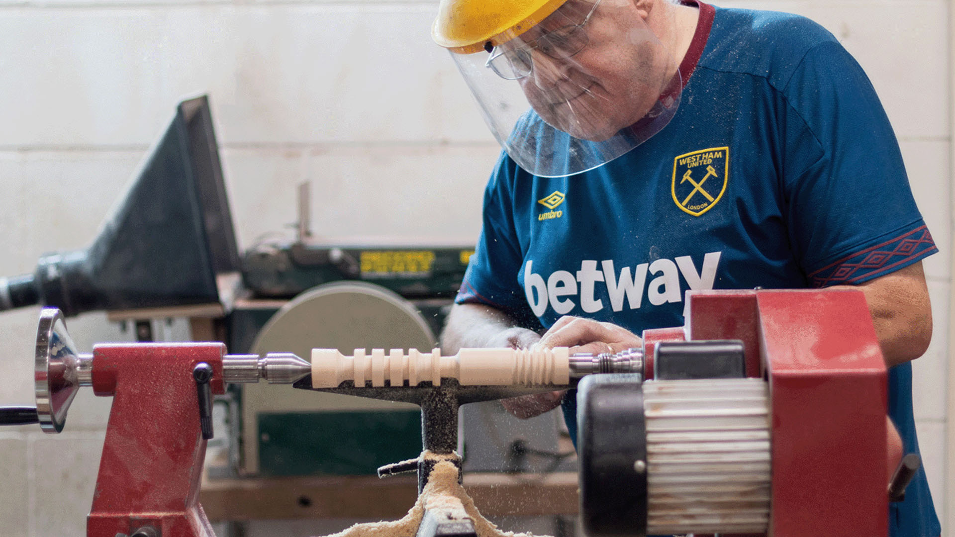 Man with clear visor using lathe