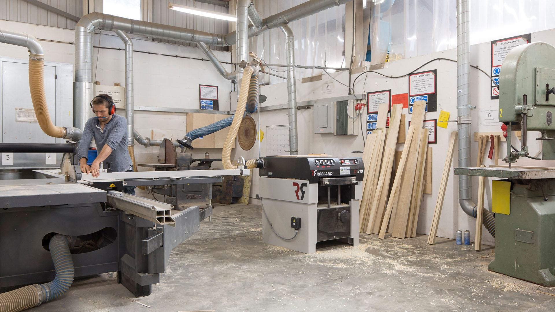 Man in dusty workshop using a table saw to left of picture