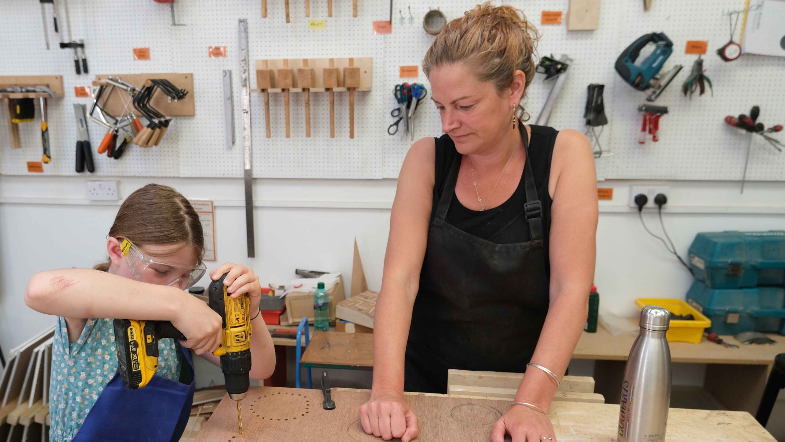 adult watching child drilling holes with electric drill