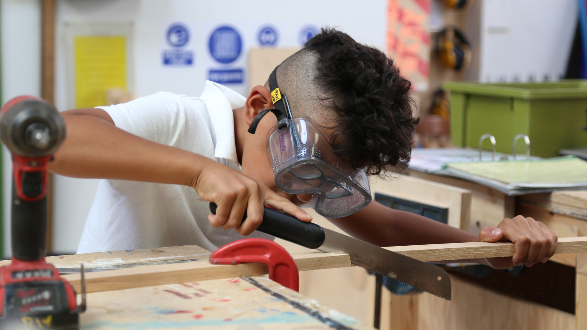 Young person with goggles using hand saw
